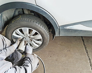 Image showing Worker changes the car's tire