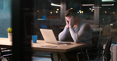 Image showing man working on laptop in dark office