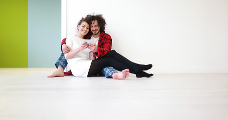 Image showing Young Couple using digital tablet on the floor