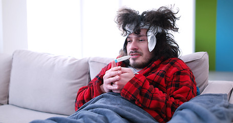 Image showing sick man is holding a cup while sitting on couch