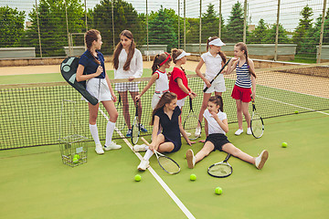 Image showing Portrait of group of girls as tennis players holding tennis racket against green grass of outdoor court