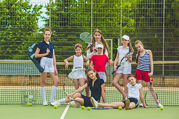 Image showing Portrait of group of girls as tennis players holding tennis racket against green grass of outdoor court