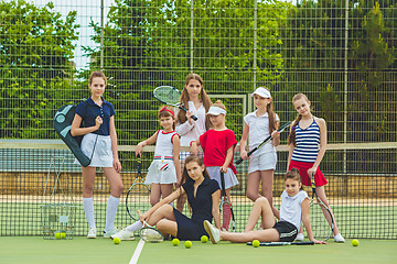 Image showing Portrait of group of girls as tennis players holding tennis racket against green grass of outdoor court