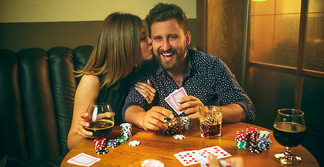 Image showing Friends sitting at wooden table. Friends having fun while playing board game.