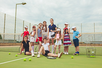 Image showing Portrait of group of girls as tennis players holding tennis racket against green grass of outdoor court