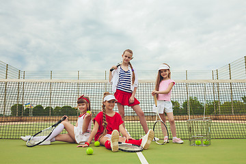 Image showing Portrait of group of girls as tennis players holding tennis racket against green grass of outdoor court