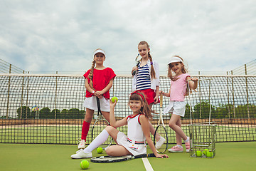 Image showing Portrait of group of girls as tennis players holding tennis racket against green grass of outdoor court