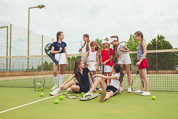 Image showing Portrait of group of girls as tennis players holding tennis racket against green grass of outdoor court