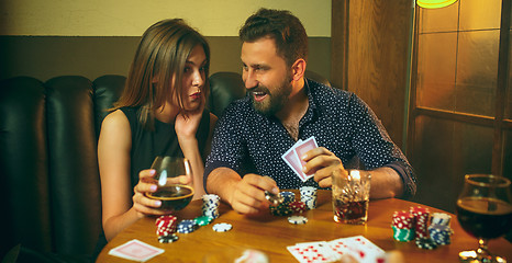 Image showing Friends sitting at wooden table. Friends having fun while playing board game.