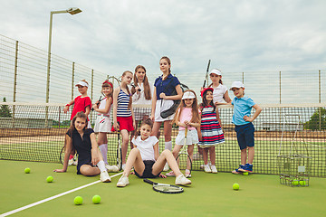 Image showing Portrait of group of girls as tennis players holding tennis racket against green grass of outdoor court