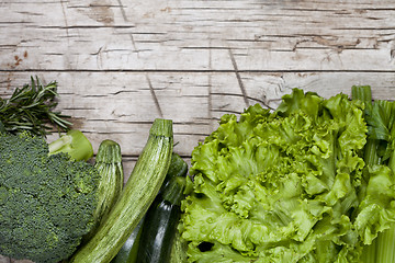 Image showing Variety of green organic vegetables on rustic wooden background.