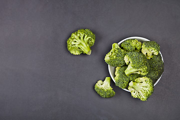 Image showing Fresh green organic broccoli in white bowl on black board backgr