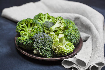 Image showing Fresh green organic broccoli in brown plate and linen napkin.