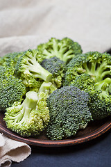 Image showing Fresh green organic broccoli in brown plate and linen napkin.