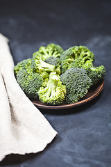 Image showing Fresh green organic broccoli in brown plate and linen napkin.