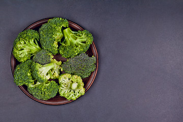 Image showing Fresh green organic broccoli in brown plate on black board backg