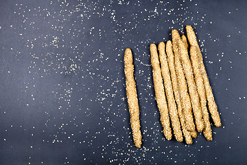 Image showing Italian grissini bread sticks with sesame seeds on black board b