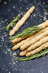 Image showing Italian grissini bread sticks with sesame and rosemary herb on b