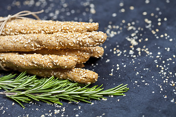 Image showing Italian grissini bread sticks with sesame and rosemary herb on b