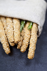 Image showing Italian grissini or salted bread sticks with rosemary herb on li