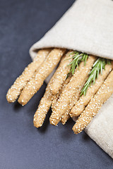 Image showing Italian grissini bread sticks with sesame and rosemary herb on b