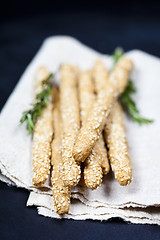 Image showing Italian grissini bread sticks with sesame and rosemary herb on b