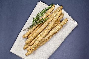 Image showing Italian grissini or salted bread sticks with rosemary herb on li