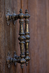 Image showing Ancient Italian metal door handles on brown wooden door. 