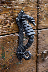 Image showing Ancient Italian metal door handle on brown wooden door. 