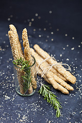 Image showing Italian grissini bread sticks with sesame and rosemary herb on b