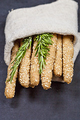 Image showing Italian grissini bread sticks with rosemary herb on linen napkin