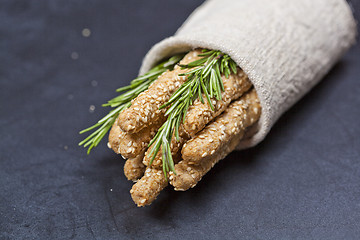 Image showing Italian grissini bread sticks with rosemary herb on linen napkin