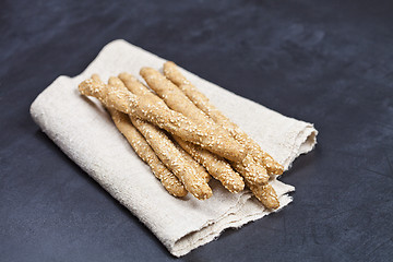 Image showing Italian grissini bread sticks with sesame on linen napkin closeu