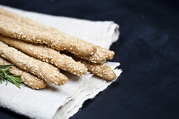 Image showing Italian grissini bread sticks with rosemary herb on linen napkin