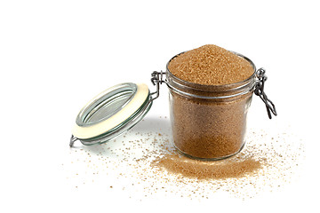 Image showing Brown cane sugar in glass jar isolated on white background.