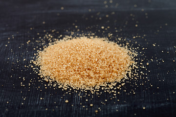 Image showing Brown cane sugar heap on black board.