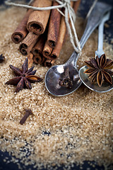 Image showing Brown cane sugar, cinnamon sticks and star anise closeup on blac