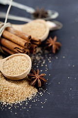 Image showing Brown cane sugar, cinnamon sticks and star anise closeup on blac