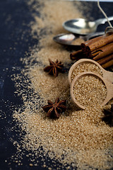 Image showing Brown cane sugar, cinnamon sticks and star anise closeup on blac