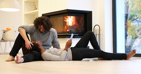 Image showing multiethnic couple using tablet computer on the floor