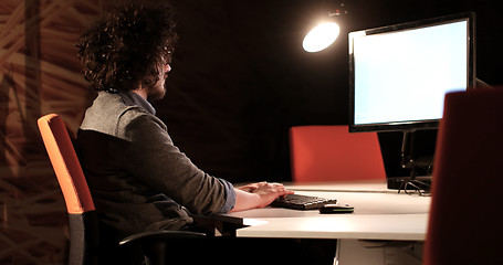 Image showing man working on computer in dark office