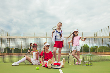 Image showing Portrait of group of girls as tennis players holding tennis racket against green grass of outdoor court