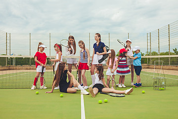 Image showing Portrait of group of girls as tennis players holding tennis racket against green grass of outdoor court