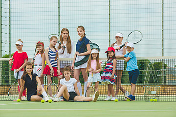 Image showing Portrait of group of girls as tennis players holding tennis racket against green grass of outdoor court