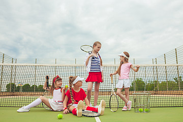 Image showing Portrait of group of girls as tennis players holding tennis racket against green grass of outdoor court