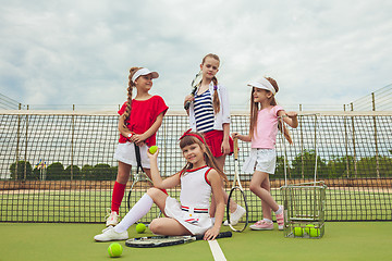 Image showing Portrait of group of girls as tennis players holding tennis racket against green grass of outdoor court