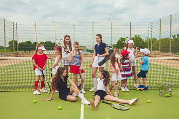 Image showing Portrait of group of girls as tennis players holding tennis racket against green grass of outdoor court