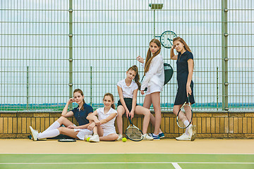 Image showing Portrait of group of girls as tennis players holding tennis racket against green grass of outdoor court