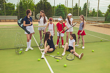 Image showing Portrait of group of girls as tennis players holding tennis racket against green grass of outdoor court