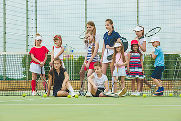 Image showing Portrait of group of girls as tennis players holding tennis racket against green grass of outdoor court